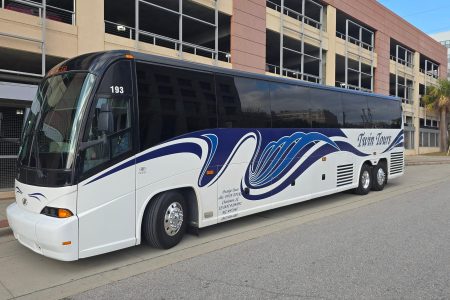 A white and blue tour bus labeled "Royal Lines" is parked beside a multi-level parking garage.
