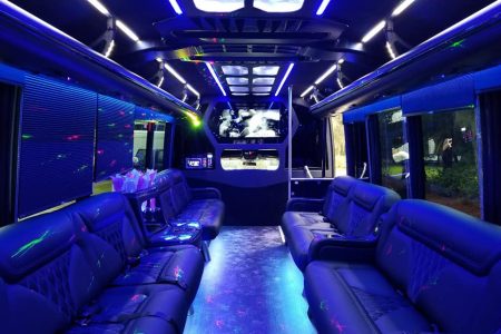Interior of a luxury party bus with leather seats, LED lighting, and a TV screen at the front.